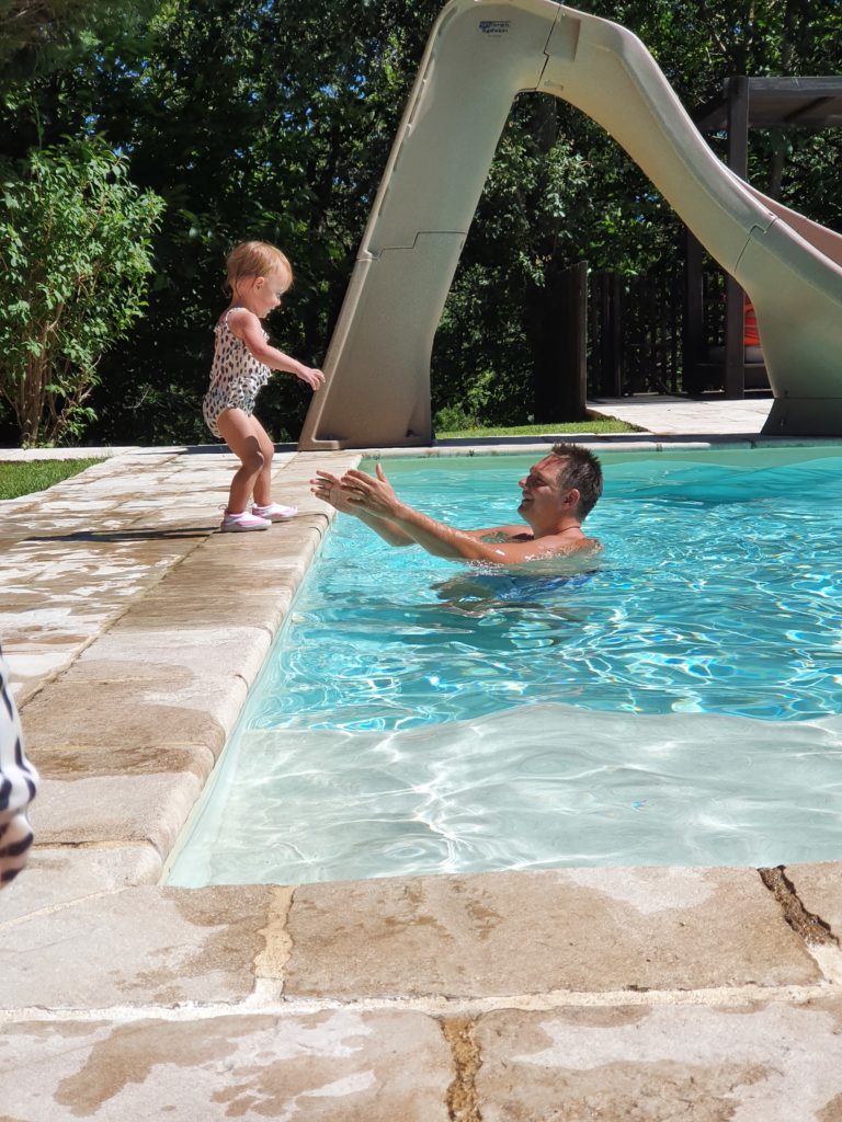 a kid by the pool and her father in the pool who extend his armssouth of France holidays with toddlers, Country Kids