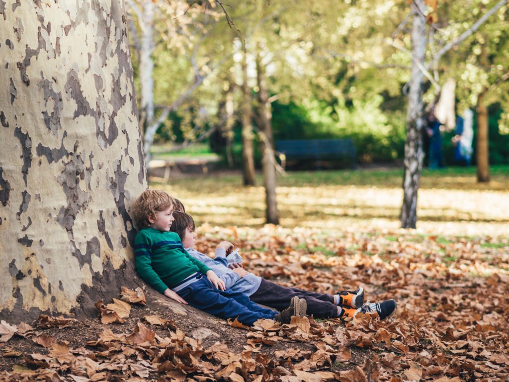 child sitting at foot of tree with leaf - child friendly holidays in south of France – country kids