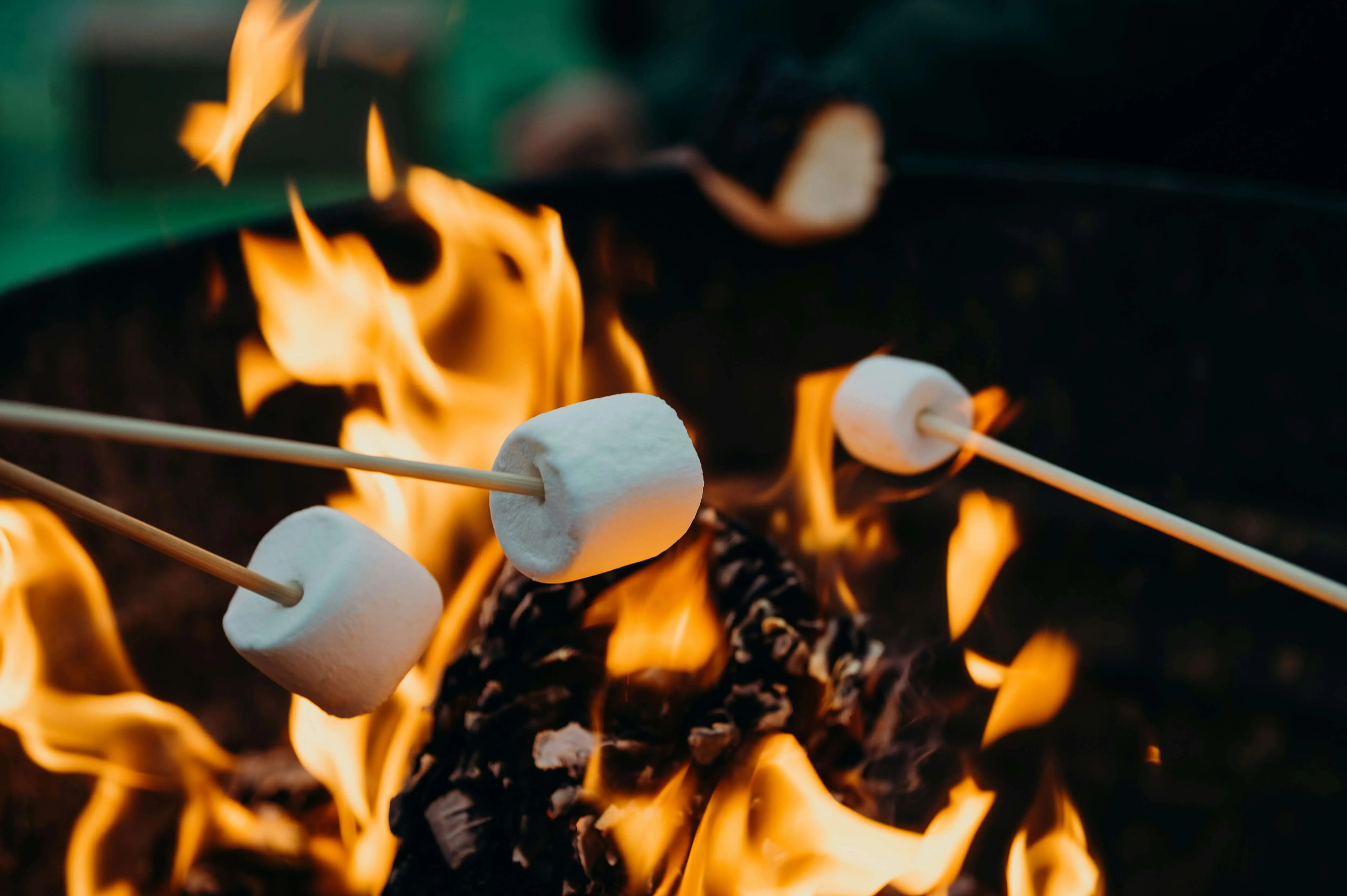 Roasting marshmallows over an open fire pit.