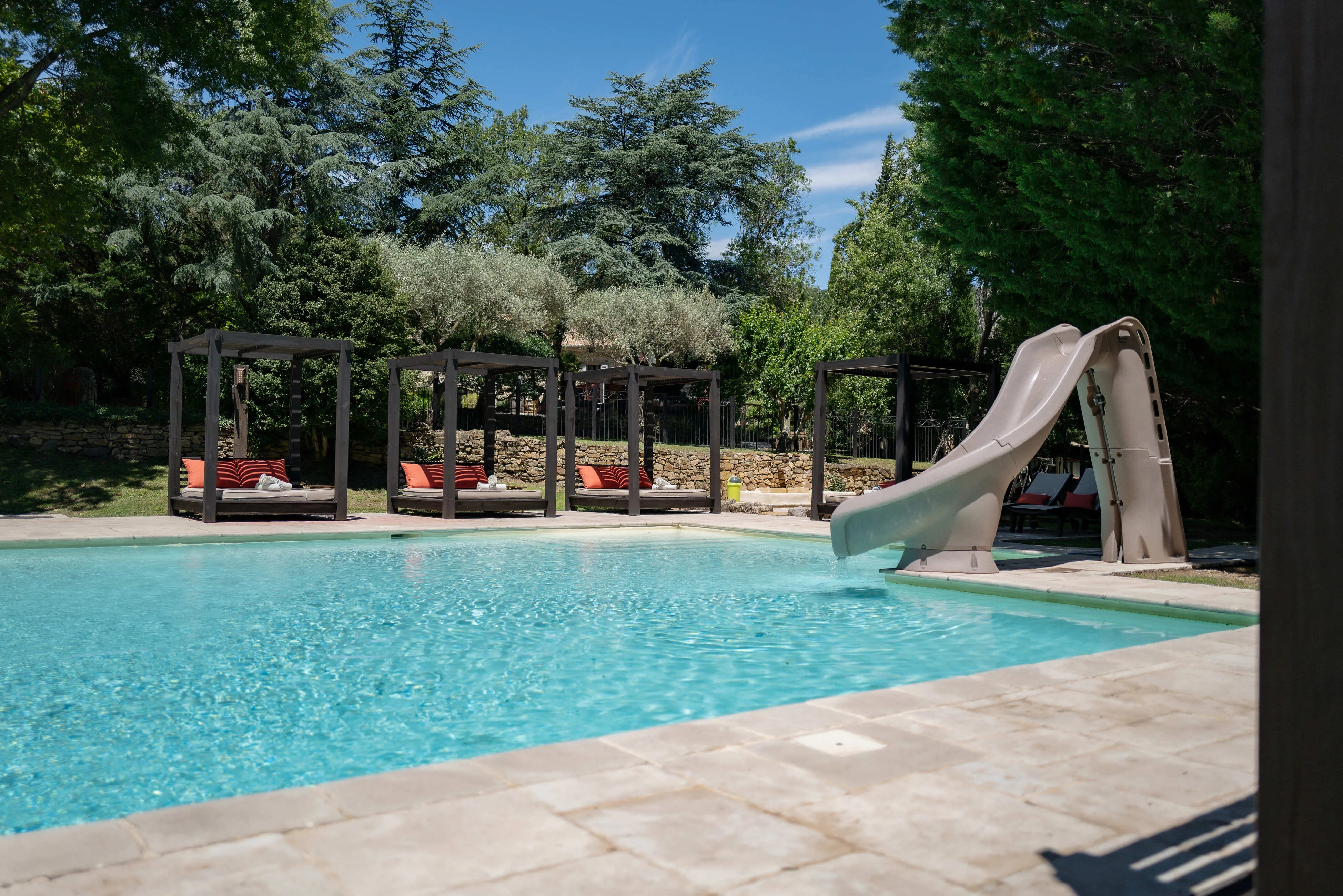 Pool with slide and outdoor loungers.