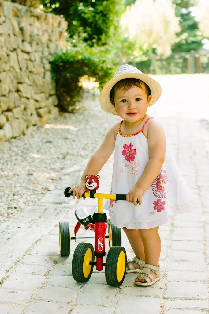 Toddler in hat with tricycle outdoors.