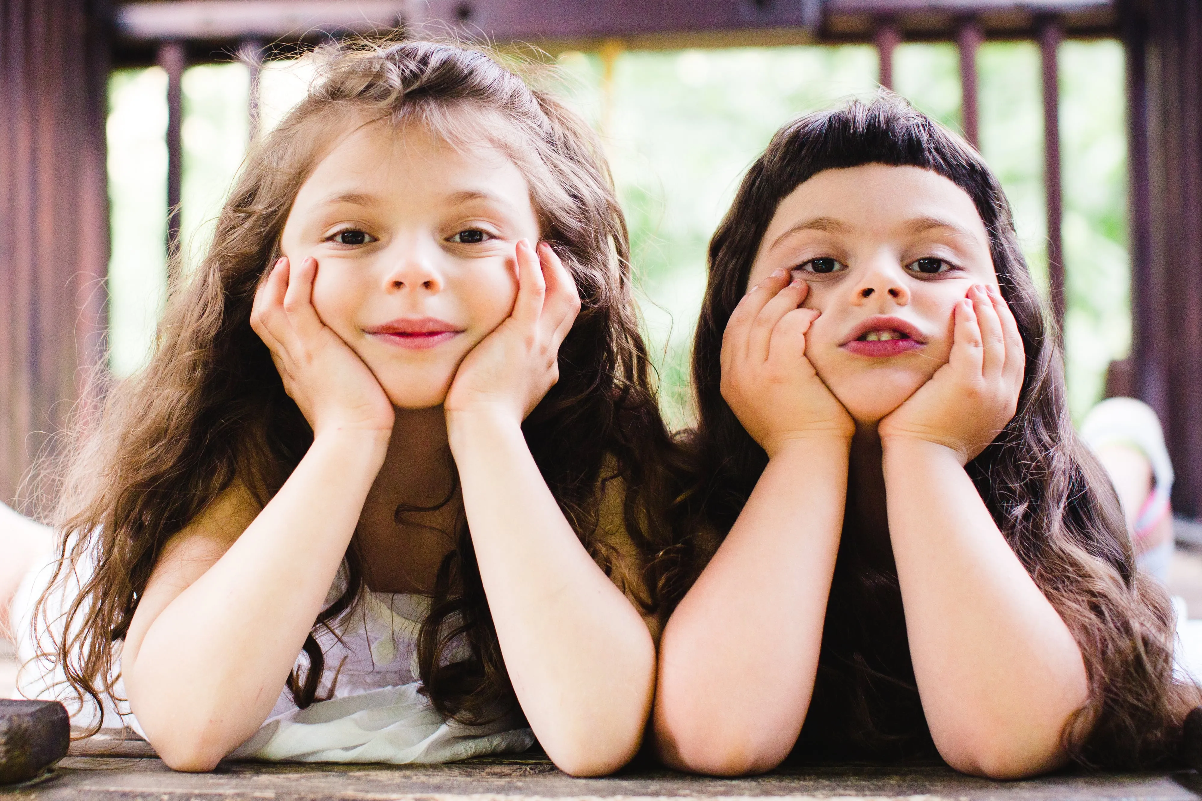 Two girls smiling, resting heads in hands.