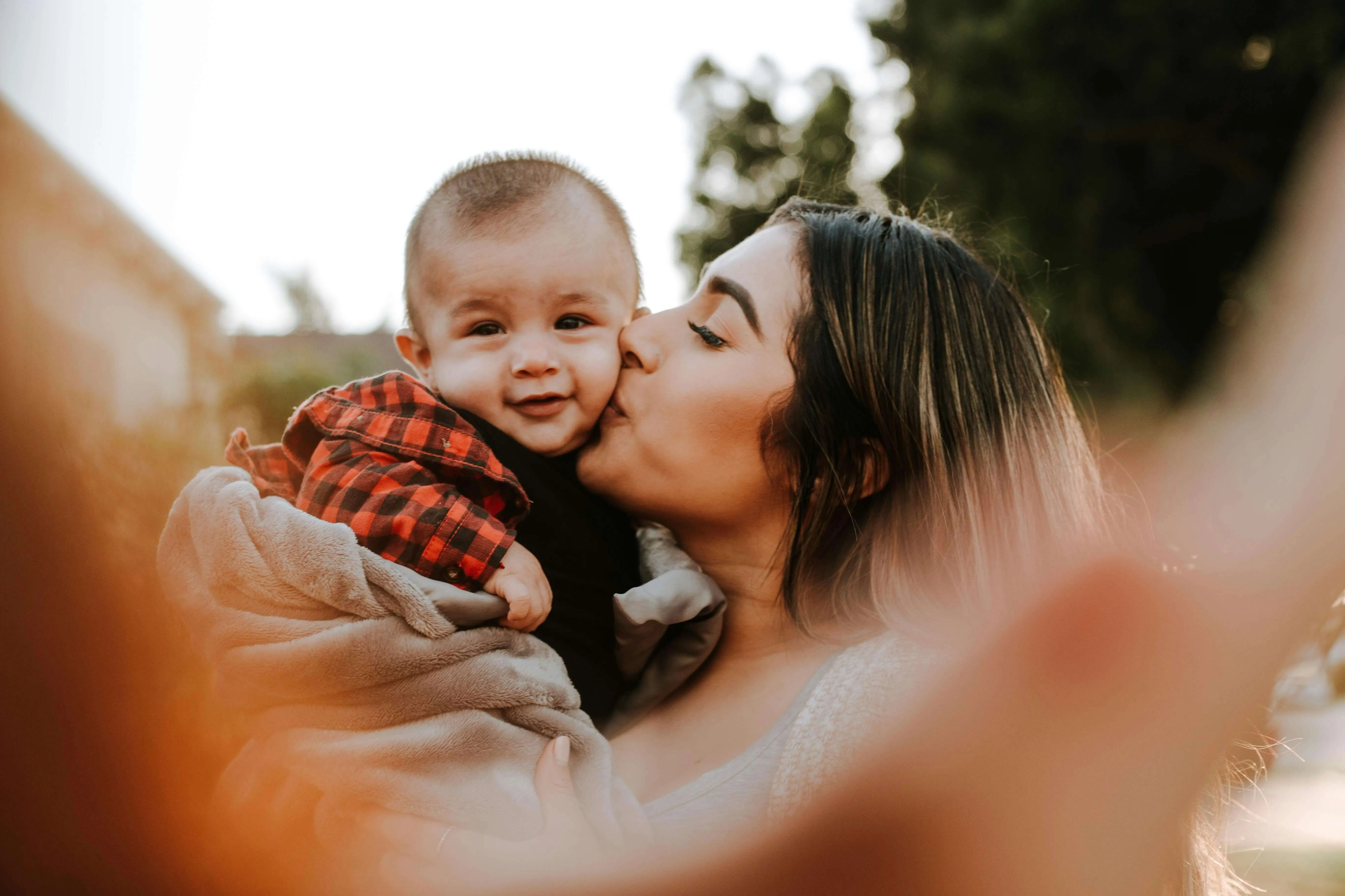 Mother kissing smiling baby outdoors