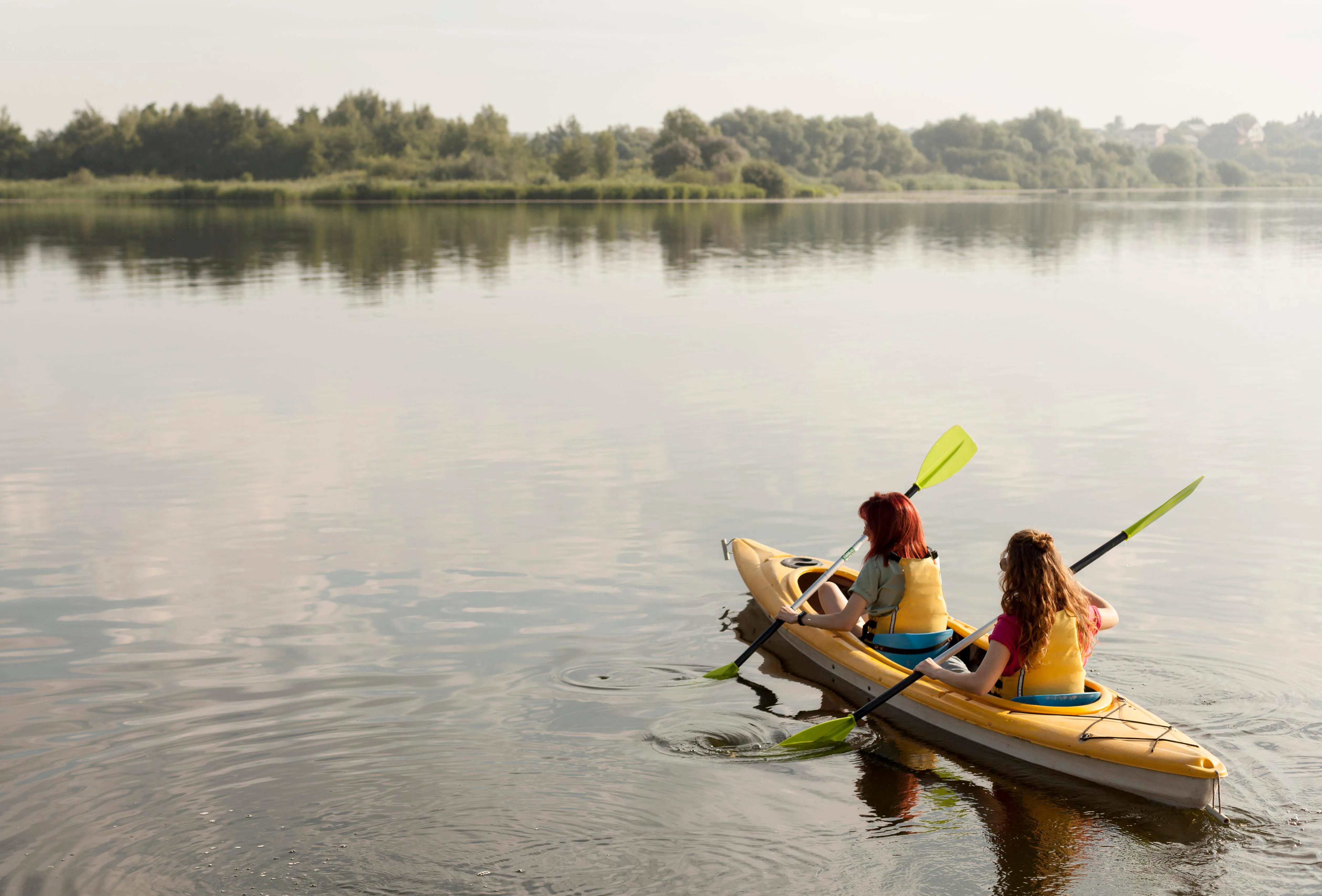 Two people kayaking on a calm lake.